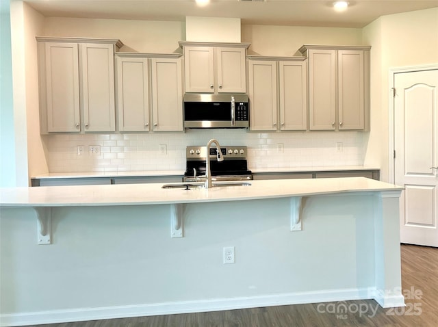 kitchen featuring gray cabinetry, stainless steel appliances, and a breakfast bar area