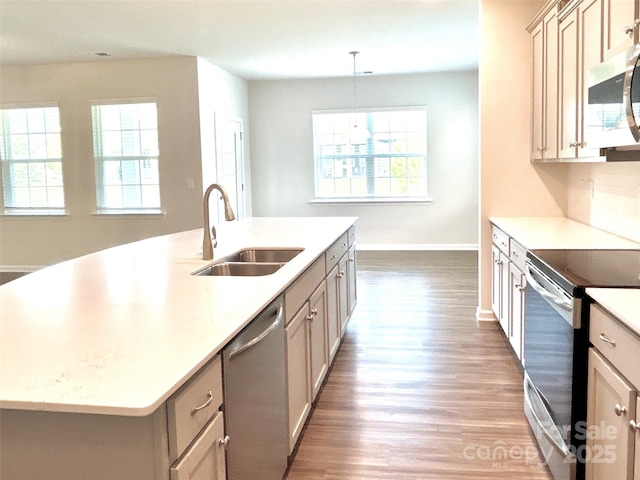 kitchen featuring sink, hanging light fixtures, wood-type flooring, a center island with sink, and appliances with stainless steel finishes