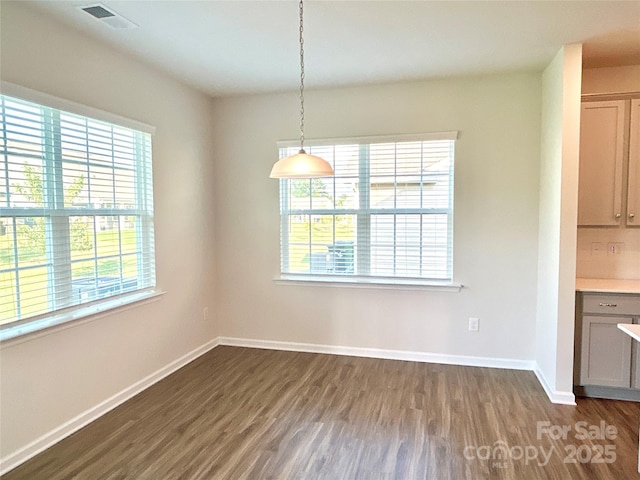 unfurnished dining area with dark wood-type flooring