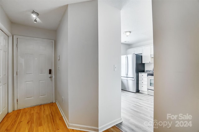 hall with baseboards and light wood finished floors