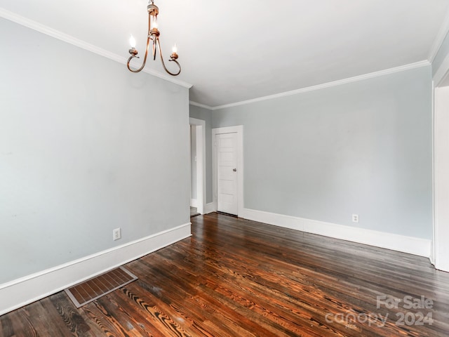 spare room featuring crown molding, dark hardwood / wood-style floors, and an inviting chandelier