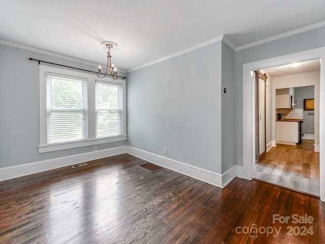 empty room featuring ornamental molding, dark hardwood / wood-style floors, and a chandelier