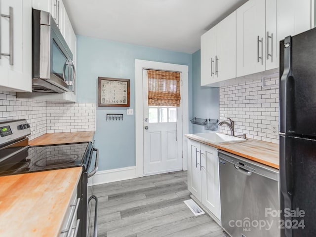 kitchen with white cabinetry, appliances with stainless steel finishes, sink, and butcher block countertops