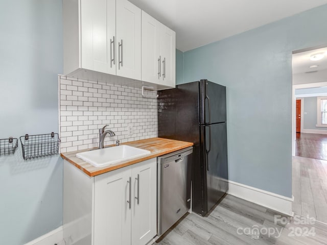 kitchen featuring white cabinetry, stainless steel dishwasher, wooden counters, and sink