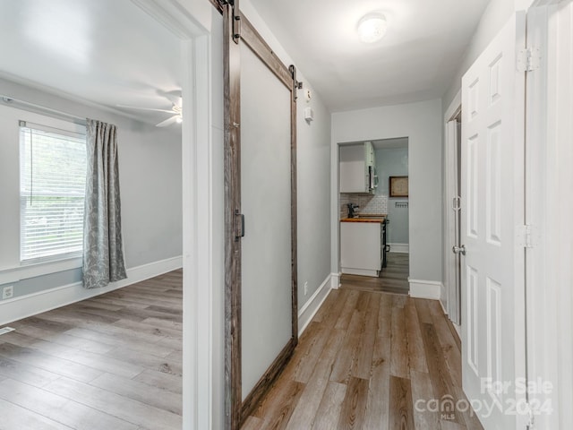 corridor with light hardwood / wood-style floors and a barn door