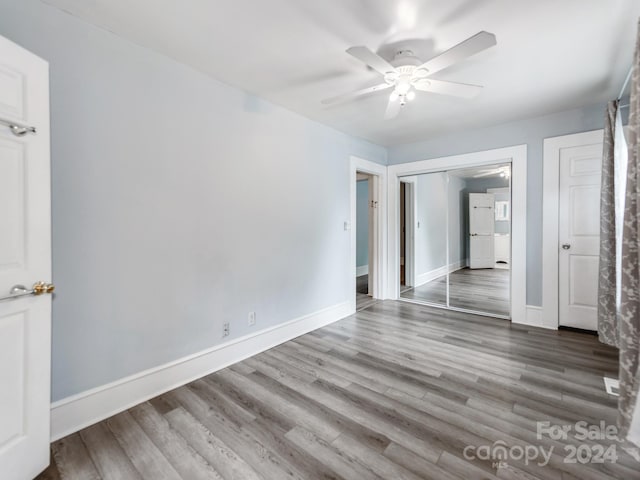 unfurnished bedroom with hardwood / wood-style floors, a closet, and ceiling fan