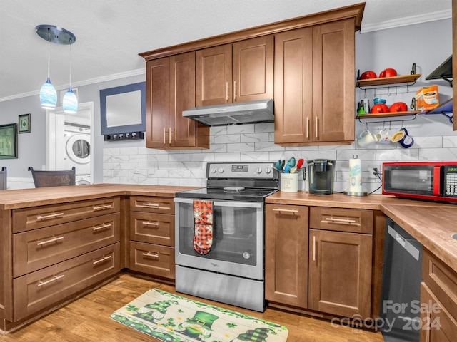 kitchen with butcher block countertops, hanging light fixtures, stainless steel appliances, stacked washer / dryer, and ornamental molding