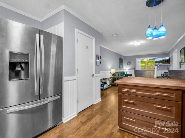 kitchen with crown molding, wooden counters, hanging light fixtures, wood-type flooring, and stainless steel fridge with ice dispenser