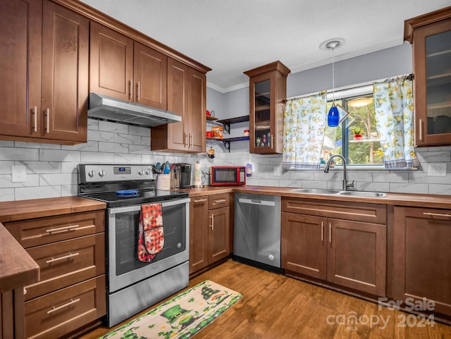 kitchen featuring tasteful backsplash, stainless steel appliances, light hardwood / wood-style floors, sink, and decorative light fixtures