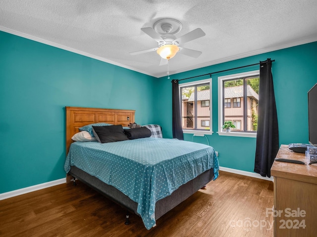 bedroom with ceiling fan, dark wood-type flooring, ornamental molding, and a textured ceiling