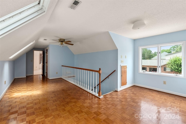 additional living space with vaulted ceiling, ceiling fan, parquet floors, and a textured ceiling