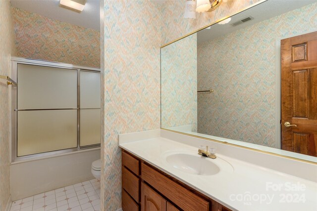 full bathroom with tile patterned floors, vanity, toilet, and shower / bath combination with glass door