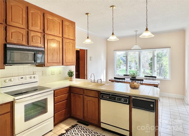 kitchen featuring kitchen peninsula, pendant lighting, white appliances, and sink