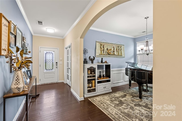 entryway featuring arched walkways, dark wood-style flooring, crown molding, a notable chandelier, and visible vents