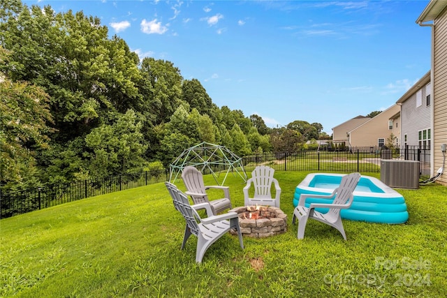 view of yard with an outdoor fire pit, central AC unit, and fence