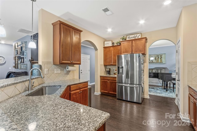 kitchen with visible vents, brown cabinetry, stainless steel fridge with ice dispenser, decorative light fixtures, and a sink