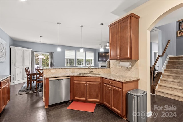 kitchen with brown cabinetry, decorative light fixtures, a peninsula, stainless steel dishwasher, and a sink