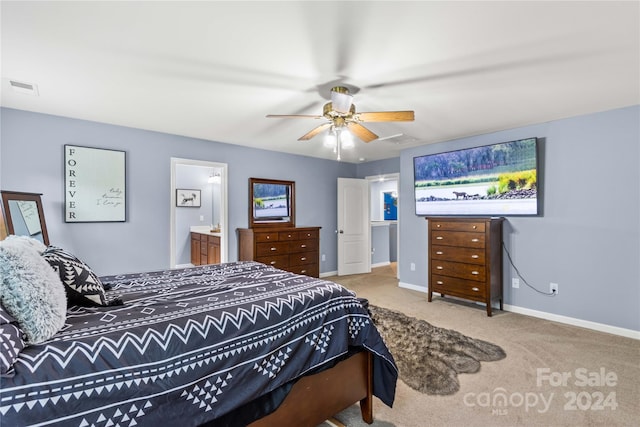 carpeted bedroom with ensuite bath, baseboards, visible vents, and a ceiling fan