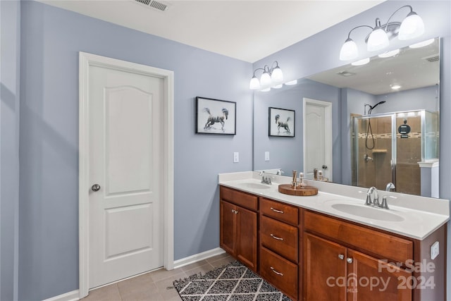 bathroom with a stall shower, a sink, visible vents, and tile patterned floors