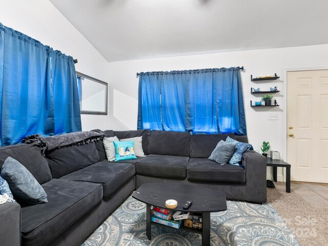 living area with lofted ceiling, light carpet, and light tile patterned floors