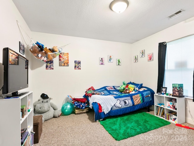 bedroom with carpet floors, visible vents, and a textured ceiling