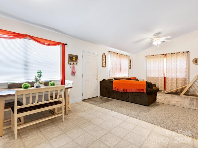 living area with lofted ceiling, plenty of natural light, a ceiling fan, and baseboards