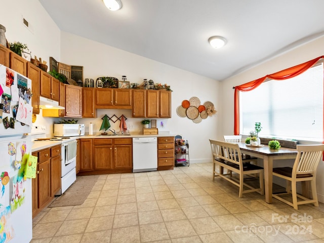 kitchen featuring under cabinet range hood, white appliances, a sink, light countertops, and brown cabinetry