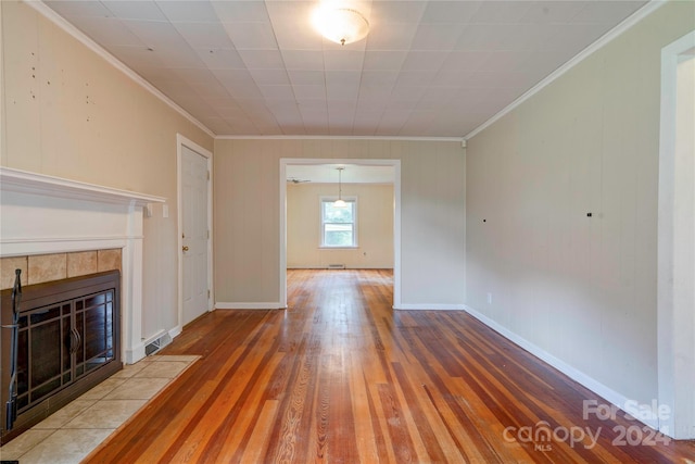 unfurnished living room featuring wood-type flooring, a tile fireplace, and crown molding