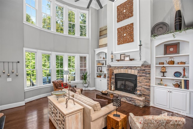 living room with a stone fireplace, dark hardwood / wood-style floors, a high ceiling, and a wealth of natural light