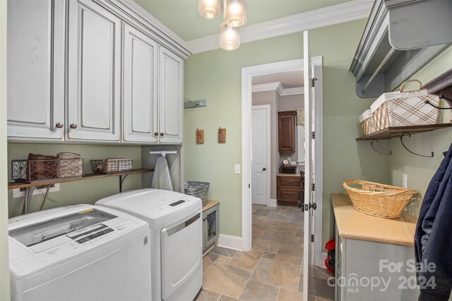 laundry room with light tile patterned flooring, cabinets, washing machine and dryer, and ornamental molding