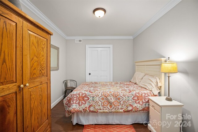 bedroom with dark wood-type flooring and ornamental molding