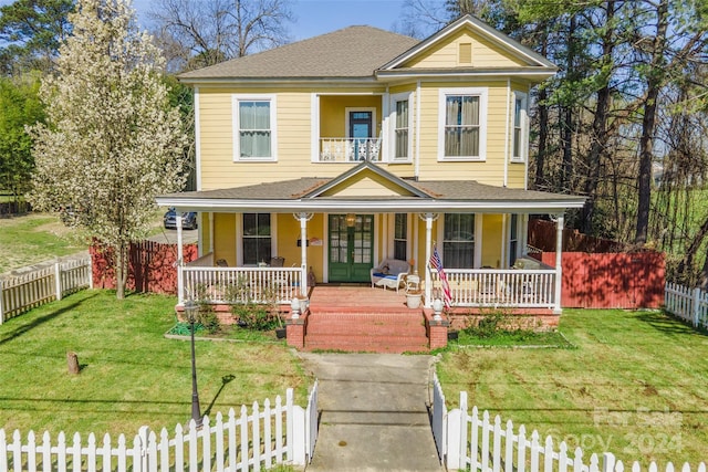 victorian-style house with covered porch, a fenced front yard, and french doors