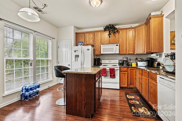 kitchen featuring dark hardwood / wood-style flooring, dark stone counters, a center island, and white appliances