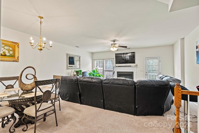 living area with light carpet, ceiling fan with notable chandelier, and a fireplace