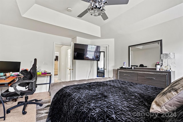 carpeted bedroom featuring ceiling fan and a raised ceiling