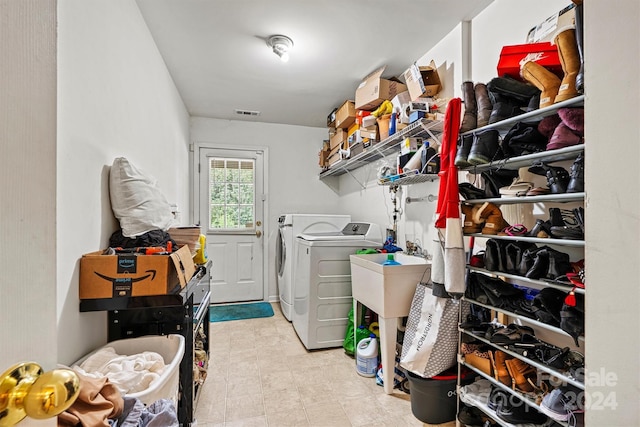 washroom featuring laundry area, visible vents, washer and clothes dryer, tile patterned floors, and a sink