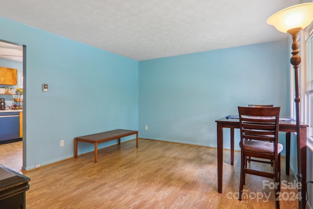 dining area with a textured ceiling and light hardwood / wood-style floors