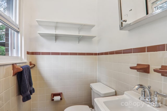 bathroom with sink, tile walls, and toilet