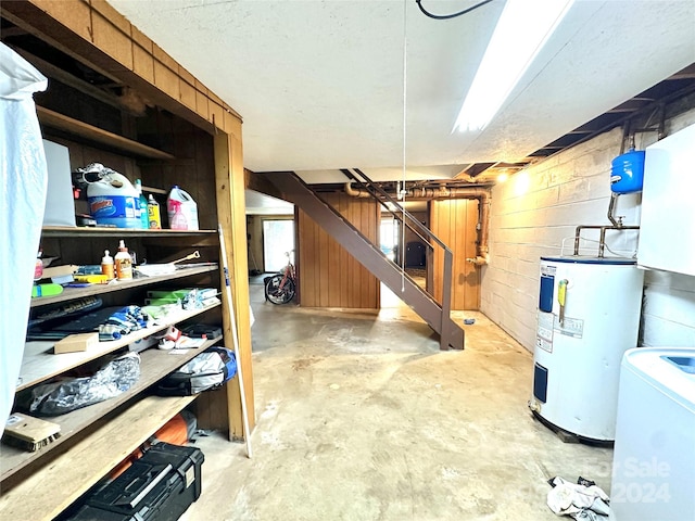 basement with wooden walls, washer / clothes dryer, and water heater