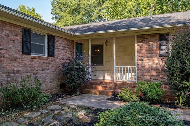 view of exterior entry with brick siding and crawl space