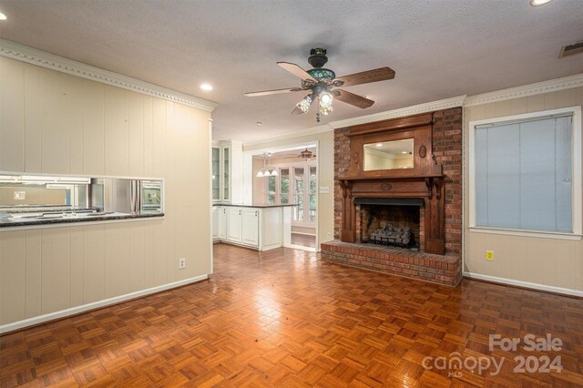 unfurnished living room with crown molding, a textured ceiling, parquet flooring, a brick fireplace, and ceiling fan