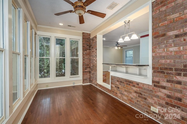 interior space featuring ornamental molding, dark hardwood / wood-style flooring, brick wall, and ceiling fan