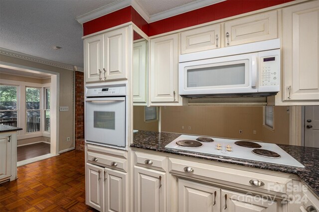 kitchen featuring dark parquet flooring, white appliances, white cabinetry, and a textured ceiling