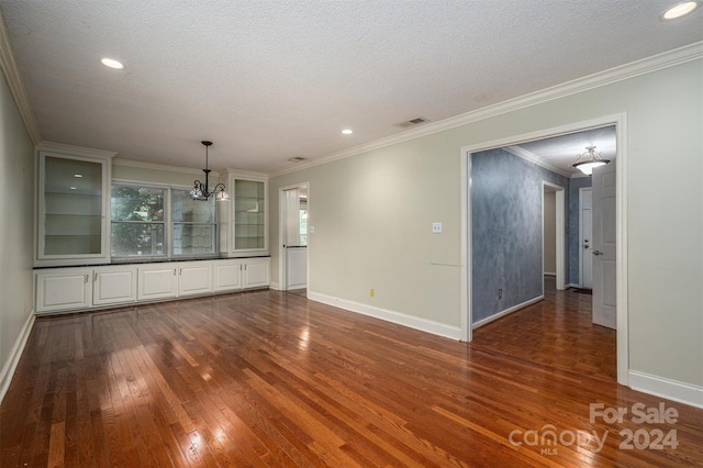 spare room featuring a textured ceiling, ornamental molding, dark wood finished floors, and visible vents