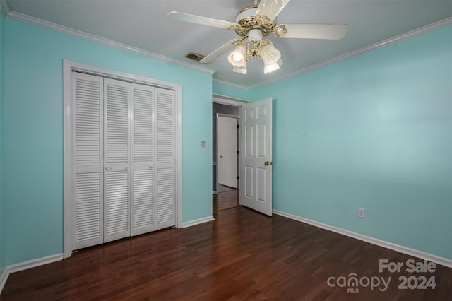 unfurnished bedroom with crown molding, dark hardwood / wood-style flooring, ceiling fan, and a closet