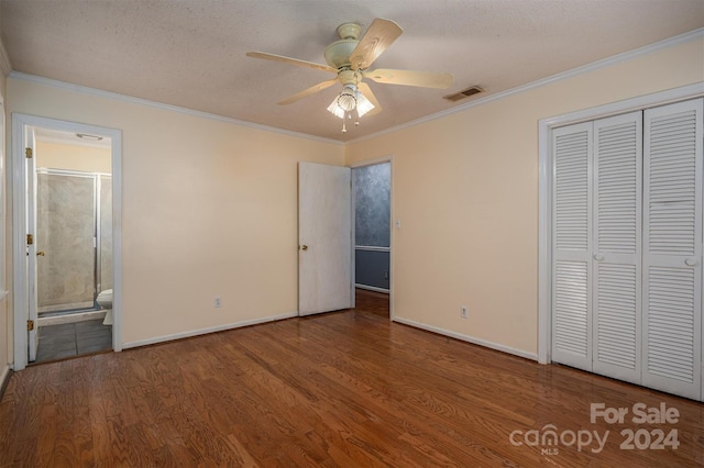 unfurnished bedroom with crown molding, dark hardwood / wood-style flooring, a closet, ceiling fan, and connected bathroom