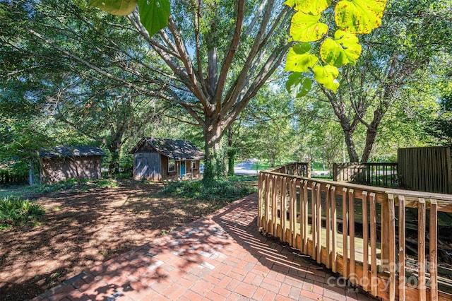 view of patio featuring a wooden deck and a storage shed