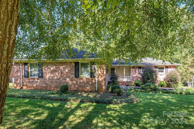 single story home featuring a porch, brick siding, and a front lawn