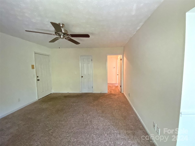 spare room with a textured ceiling, carpet flooring, and ceiling fan