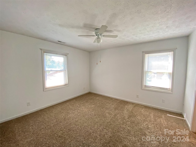 spare room featuring a textured ceiling, ceiling fan, and carpet floors